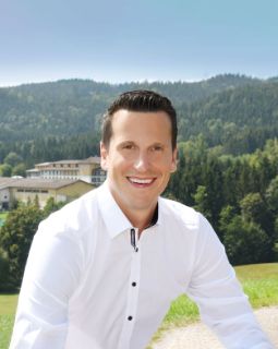 Person lächelt in die Kamera im Hintergrund der Aldiana Club Ampflwang