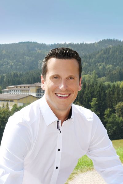 Person lächelt in die Kamera im Hintergrund der Aldiana Club Ampflwang